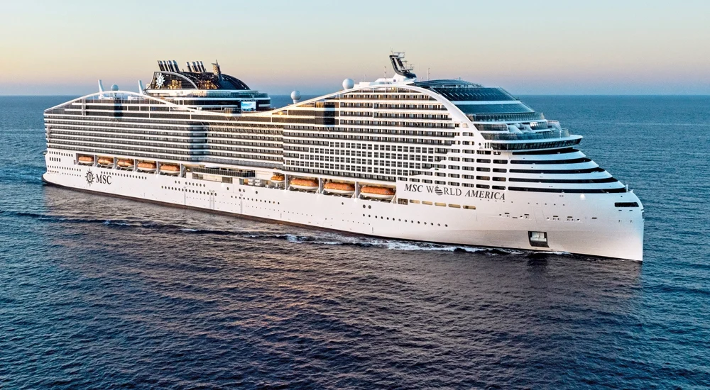 MSC World America cruiseschip op zee met meerdere dekken en wit romp, gefotografeerd bij zonsopgang.