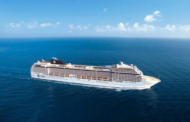 Cruiseschip MSC Orchestra vaart op open zee onder blauwe hemel met wolken