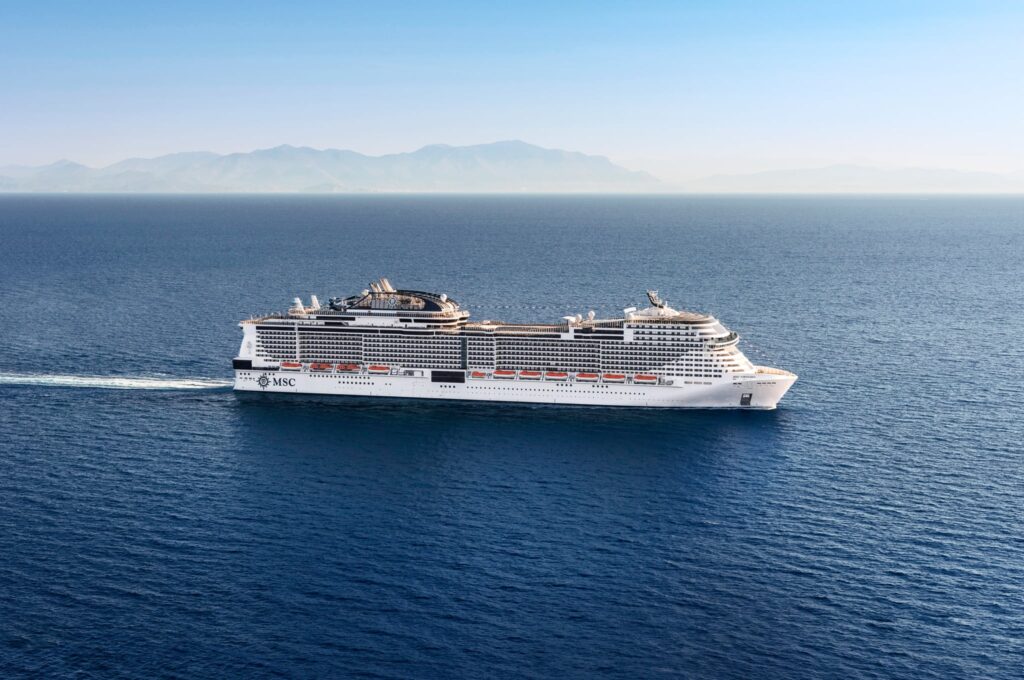 MSC Virtuosa cruiseschip op zee met bergkust op achtergrond